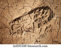 Imprint of the shoe on the dried and cracked mud. Closeup shot.