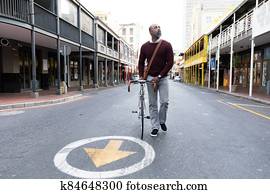 African American man walking beside his bike in the city street African American man walking beside his bike in the city street