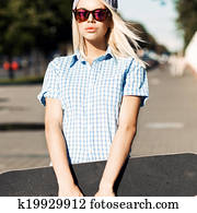 Beautiful blonde girl in short shorts with skateboard