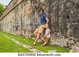 Dad and son on background of Fort Cornwallis in Georgetown, Penang, is a star fort built by the British East India Company in the late 18th century, it is the largest standing fort in Malaysia. Traveling with children concept