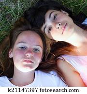 Two young girl lying on grass having good time.