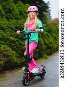 Happy girl standing on electric scooter outdoor