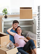 adorable couple sitting on the floor in their new house during removal looking the front