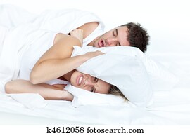 upset woman in bed with her boyfriend snoring 