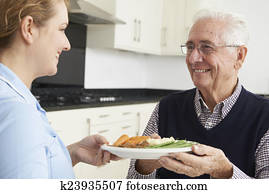 Carer Serving Lunch To Senior Man
