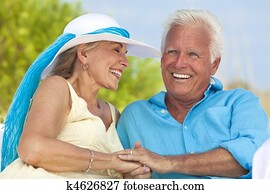 Happy Senior Couple Holding Hands & Laughing at the Beach