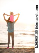 Baby girl sitting on shoulders of mother and rejoicing while on 