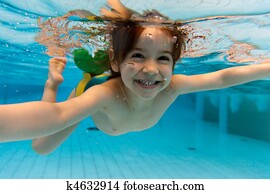 The girl smiles, swimming under water in the pool