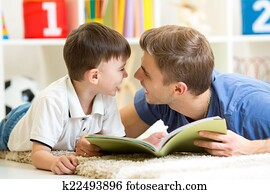 father and his kid son reading a book on floor at home