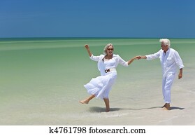 Happy Senior Couple Dancing Holding Hands on A Tropical Beach