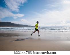 Young Man In Fitness Clothing Running Along Beach
