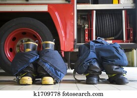 Two firefighting uniforms on floor by fire engine