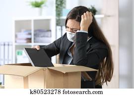 Fired executive with mask packing belongings at office Fired executive with mask packing belongings at office