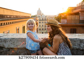 Mother kneeling by daughter above Rome at sunset
