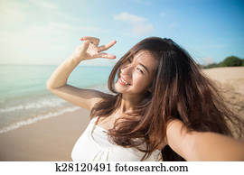 Happy young Asian woman take photos, smile to camera, victory sign hand gesture