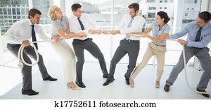 Business people playing tug of war in office