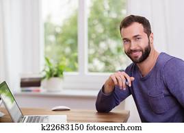 Good-looking bearded man in a home office