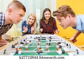 Happy friends playing table hockey