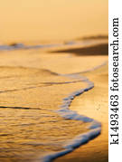 Waves lapping on beach at sunset.