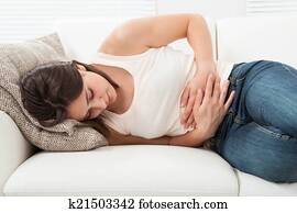 Woman Suffering From Stomachache On Sofa