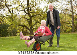 Senior Couple Man Giving Woman Ride In Wheelbarrow Senior Couple Man Giving Woman Ride In Wheelbarrow
