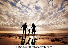 Happy family together hand in hand on the beach at sunset. Summer time, parents, child