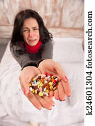 Frustrated woman lying in bed with pills