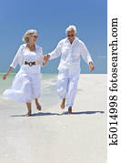 Happy Senior Couple Running Holding Hands on A Tropical Beach