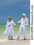 Happy Senior Couple Walking Holding Hands on A Tropical Beach