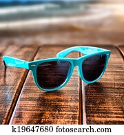 Sunglasses on wooden desk at the summer beach