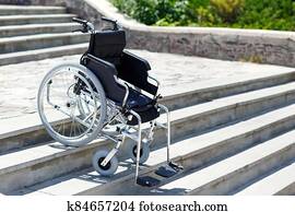 Wheelchair near the steps outdoors in the park. Wheelchair near the steps outdoors in the park.