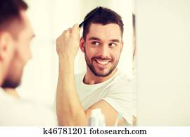 happy man brushing hair with comb at bathroom happy man brushing hair with comb at bathroom
