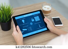 woman holding tablet computer with smart home near phone coffee