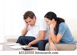 Worried couple looking at their bills on the sofa Worried couple looking at their bills on the sofa
