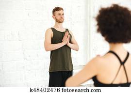 Male yoga instructor practising yoga with group of women