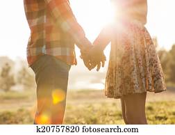Young couple in love walking in the autumn park holding hands lo Young couple in love walking in the autumn park holding hands lo