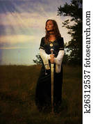 mystical medieval woman  standing  with a sword on a wild meadow