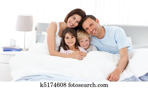 Happy children with their parents on the bed