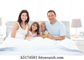 Happy family having breakfast together on the bed