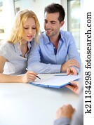 Cheerful couple signing property contract with real-estate agent