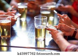 friends with beer and smartphones at bar or pub friends with beer and smartphones at bar or pub