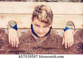 Young caucasian boy in medieval pillory, red filter