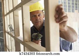 Construction Worker Building Timber Frame In New Home