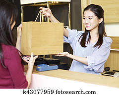 salesclerk handing merchandise to customer salesclerk handing merchandise to customer