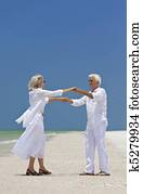 Happy Senior Couple Dancing Holding Hands on A Tropical Beach