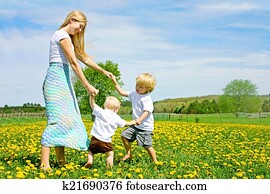 Mother and Children Playing and Dancing Outside in Flower Meadow