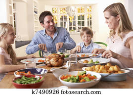 Happy family having roast chicken dinner at table