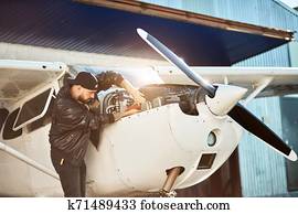 side view of young male engineer inspecting small propeller airplane side view of young male engineer inspecting small propeller airplane