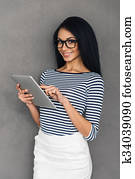 apprécier, elle, nouveau, tablet., beau, jeune, africaine, travailler, tablette numérique, et, regarder appareil-photo, à, sourire, quoique, debout, contre, gris, fond