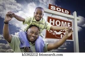 feliz, americano africano, padre, con, hijo, delante de, vendido, hogar, en venta, signo bienes raíces, y, sky.